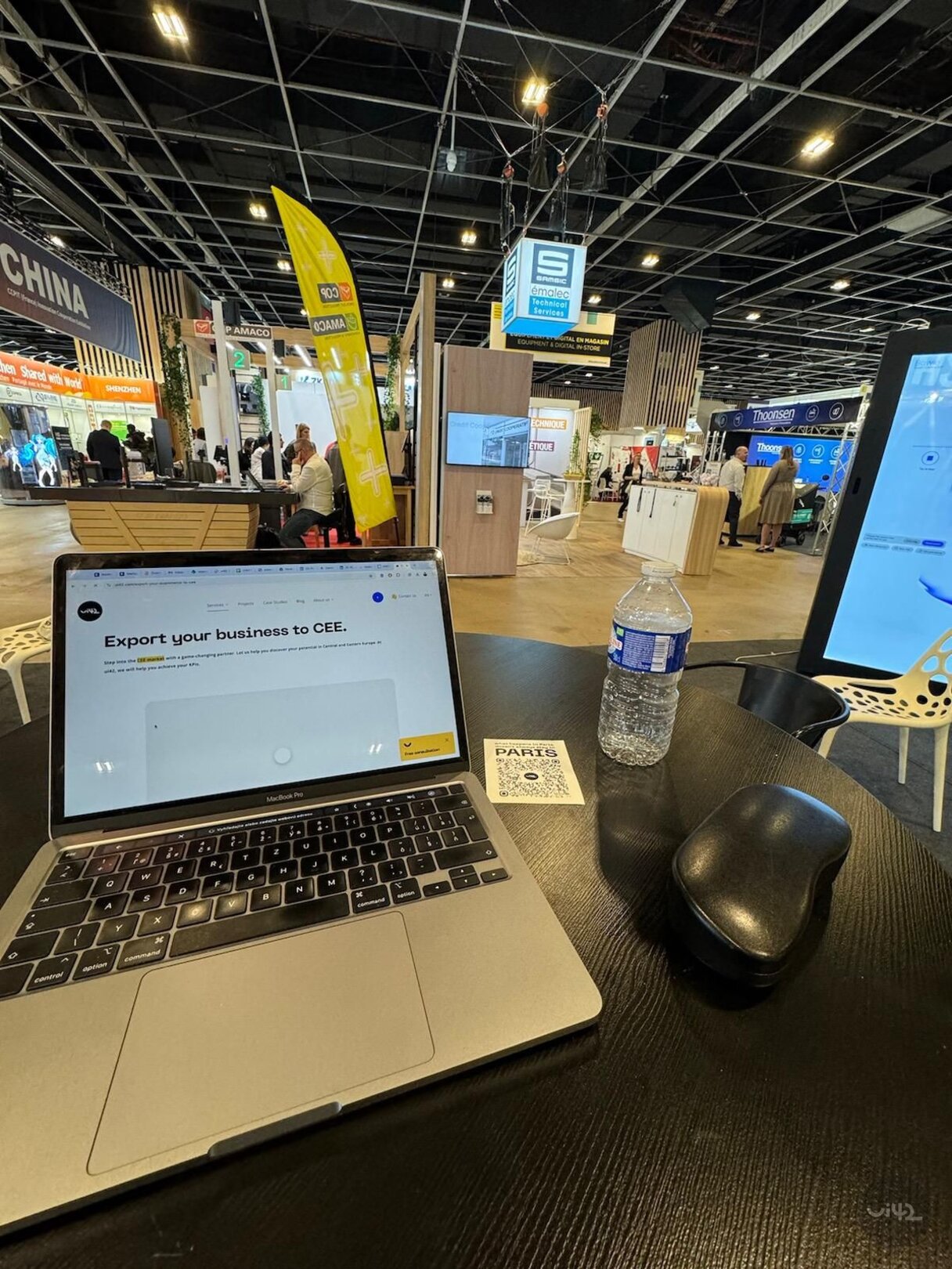 Notebook on the table with a bottle of water and a mouse at the exhibition in Paris