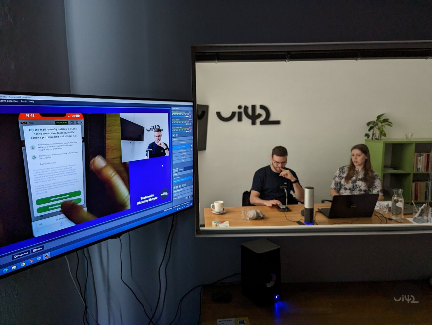 UX laboratory studio with two people at a table, with user interface testing on a mobile device taking place on the screen.